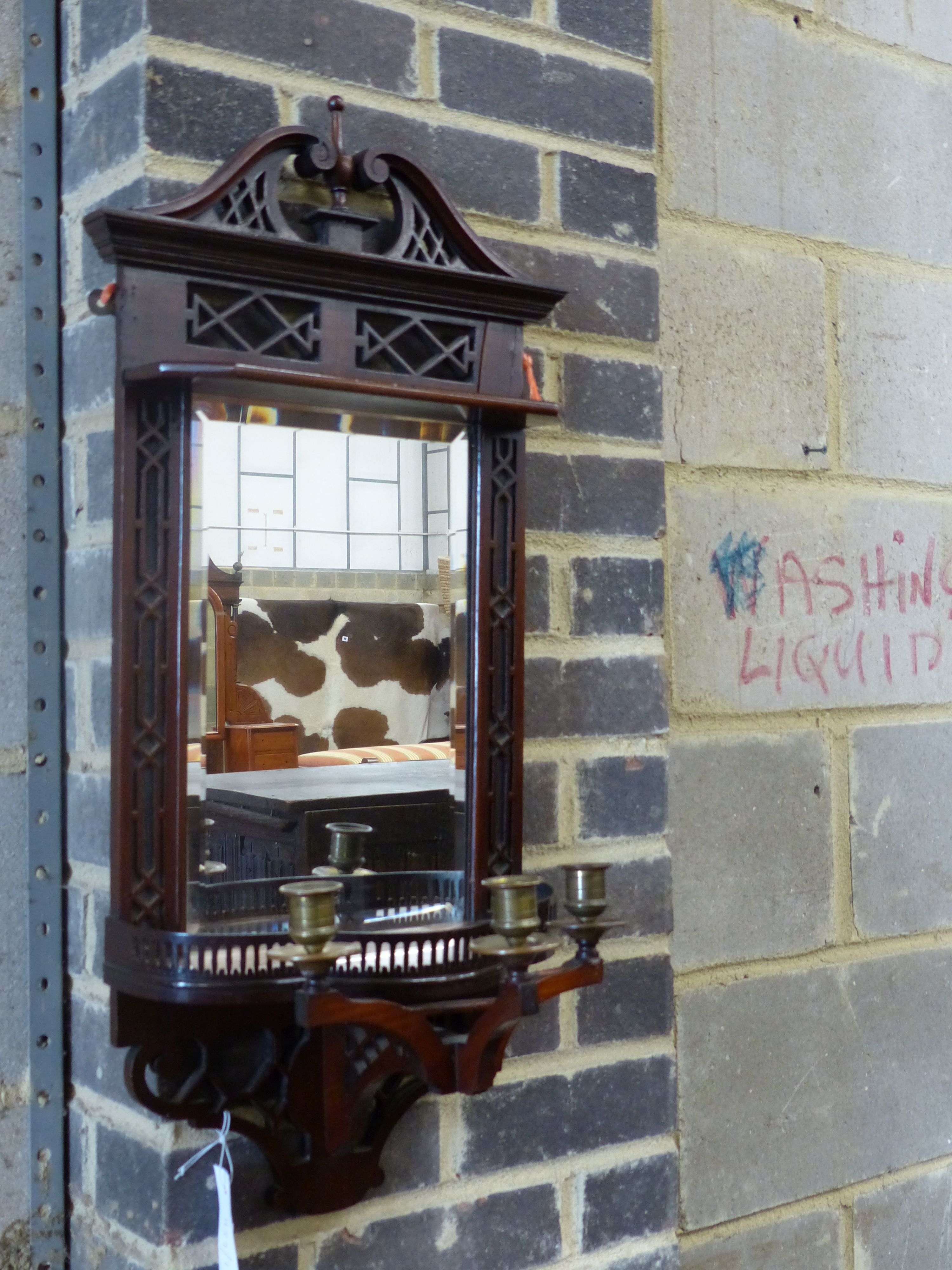 An Edwardian mahogany mirrored wall bracket with triple brass sconce, width 31cm height 75cm